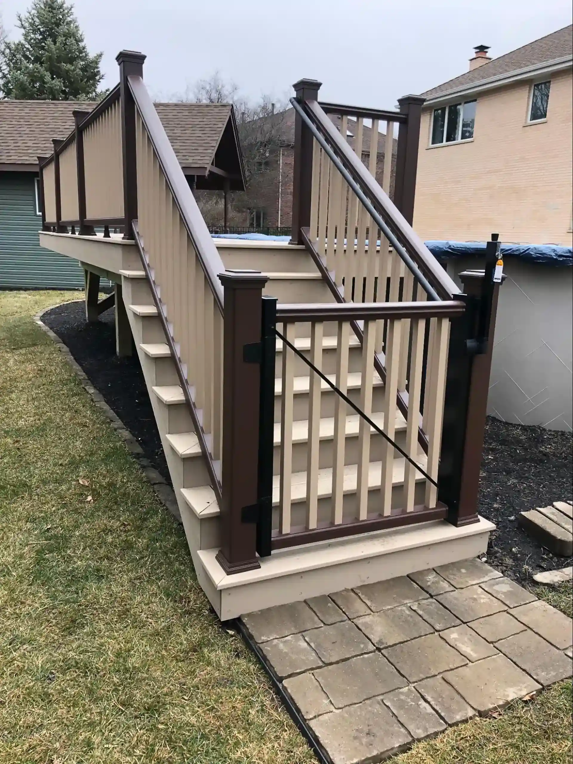 beige and brown elevated pool deck with gated staircase and vinyl railings - above the ground pool deck ideas