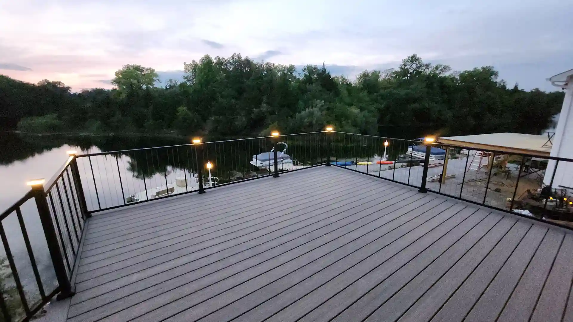 modern deck overlooking la ake at dusk with lit posts and black railing