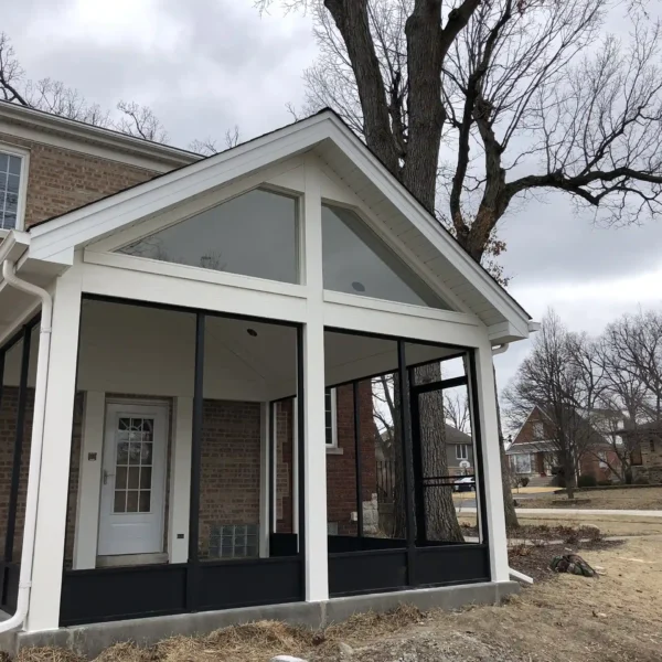 screened-in porch with a gable roof attached to a brick house.