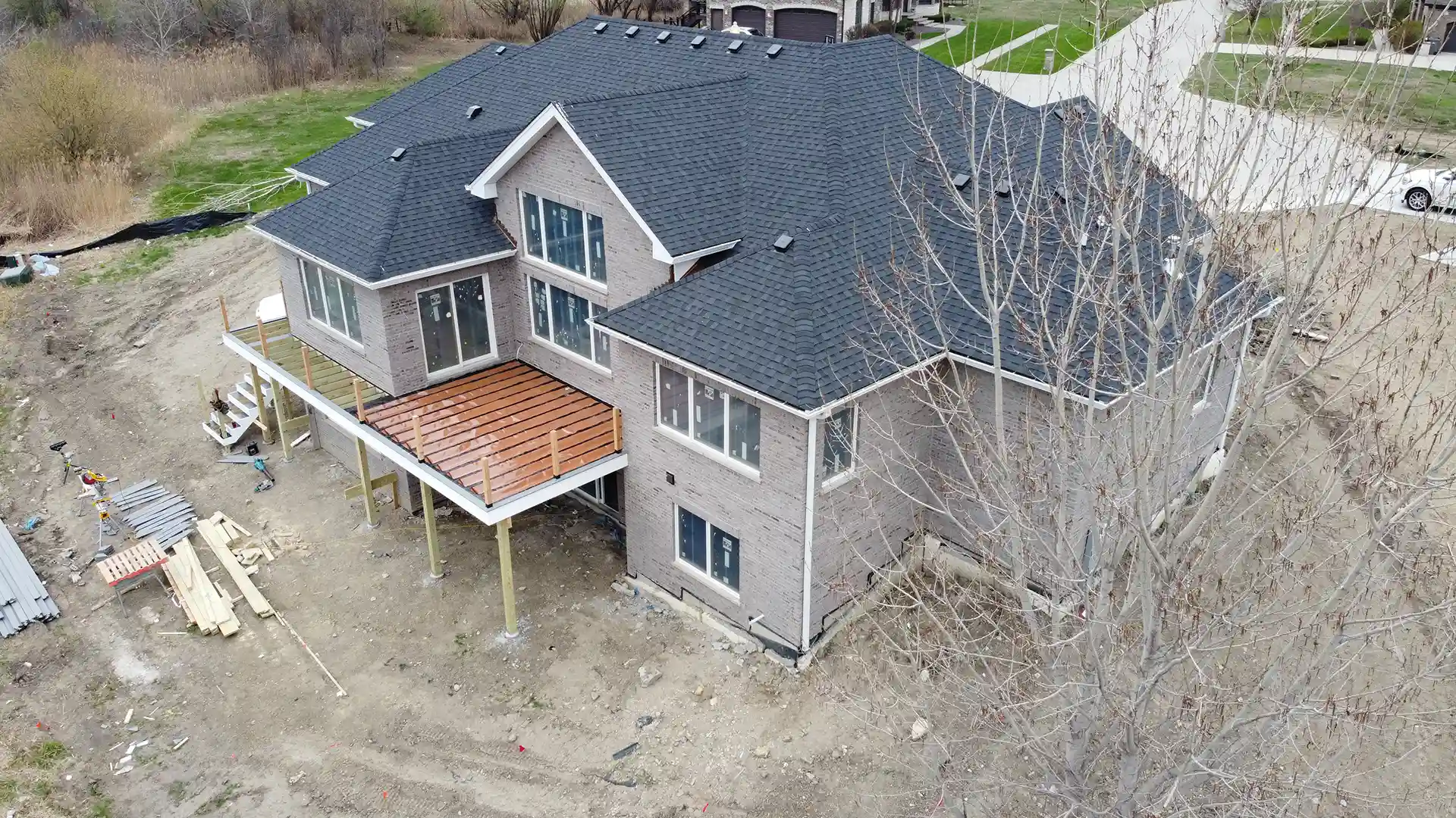 large two-story house with a partially built elevated deck under construction. 