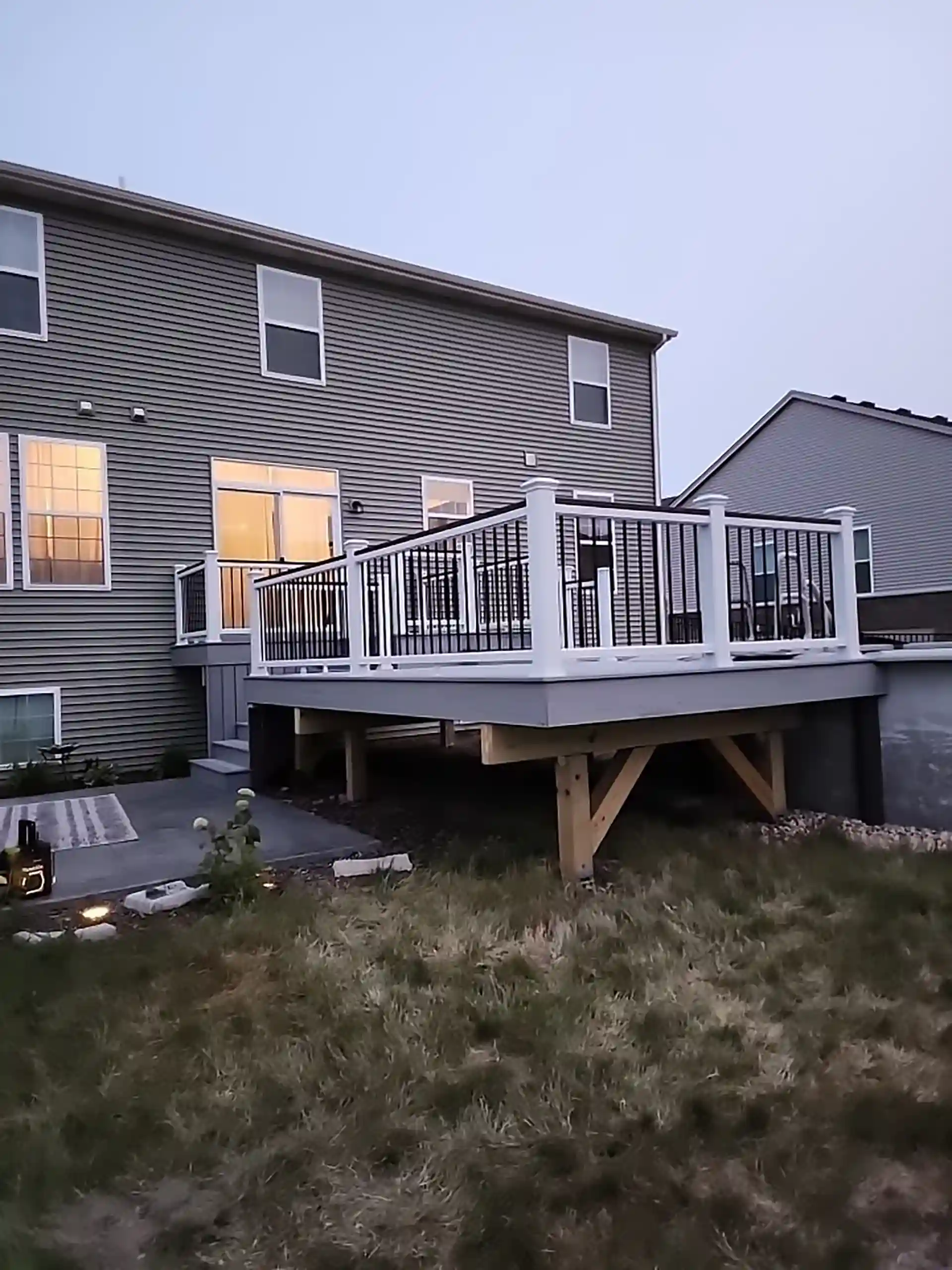 elevated backyard deck with white railings attached to a two-story house. 