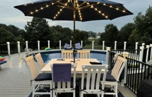 Outdoor dining area with a large umbrella and pool in the background.