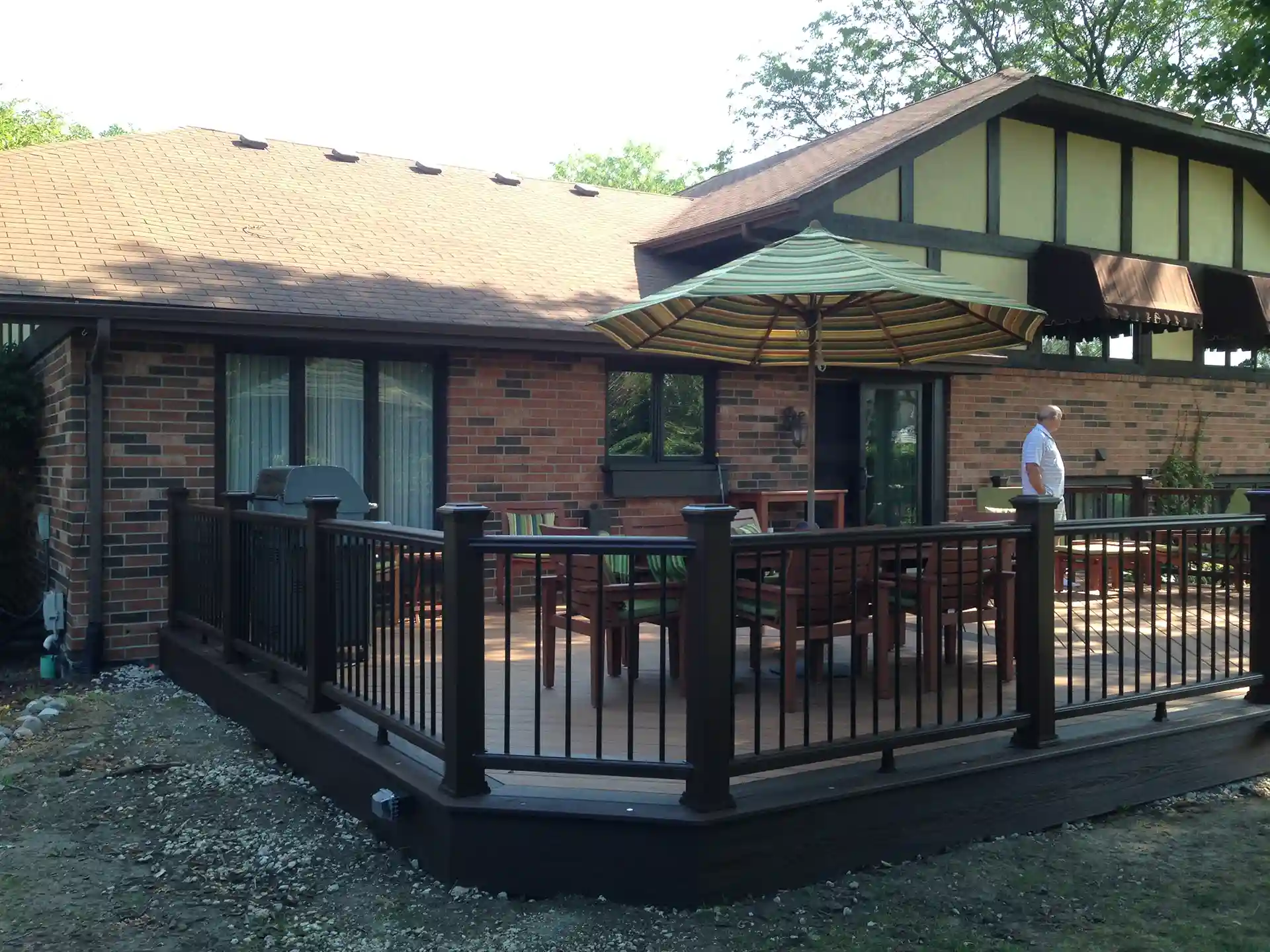deck with seating area and an umbrella, attached to a brick house.
