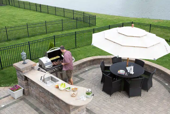 outdoor patio at the summer kitchen preparing for guests with a table and chairs with a garden umbrella alongside