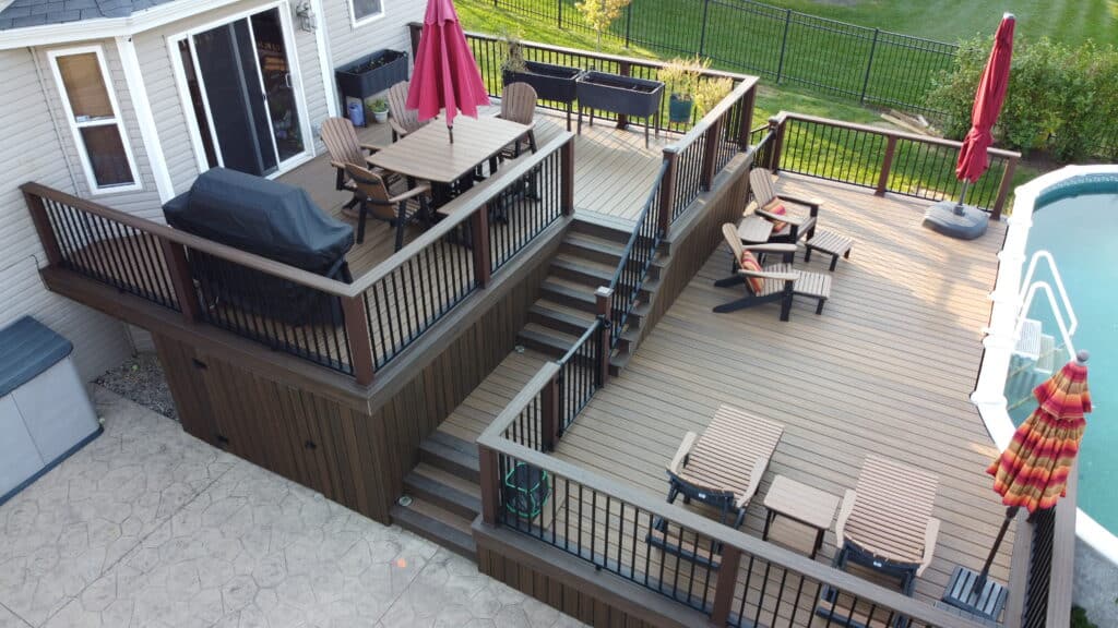 photo of a multi-level deck attached to a home that features outdoor furniture, a grill, and a pool.