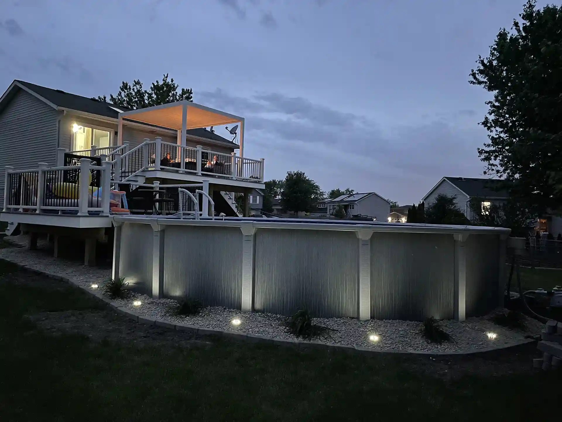 outdoor deck with lighting and a pool at dusk