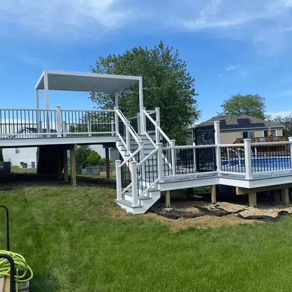 photo of a multi-level pool deck with a louvered pergola and deck steps and deck railing.